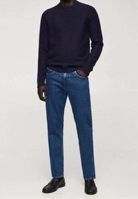 Suéter azul marino de punto texturizado, combinado con jeans rectos de un azul medio y mocasines negros. Diseño simple y clásico con acentos de canalé.