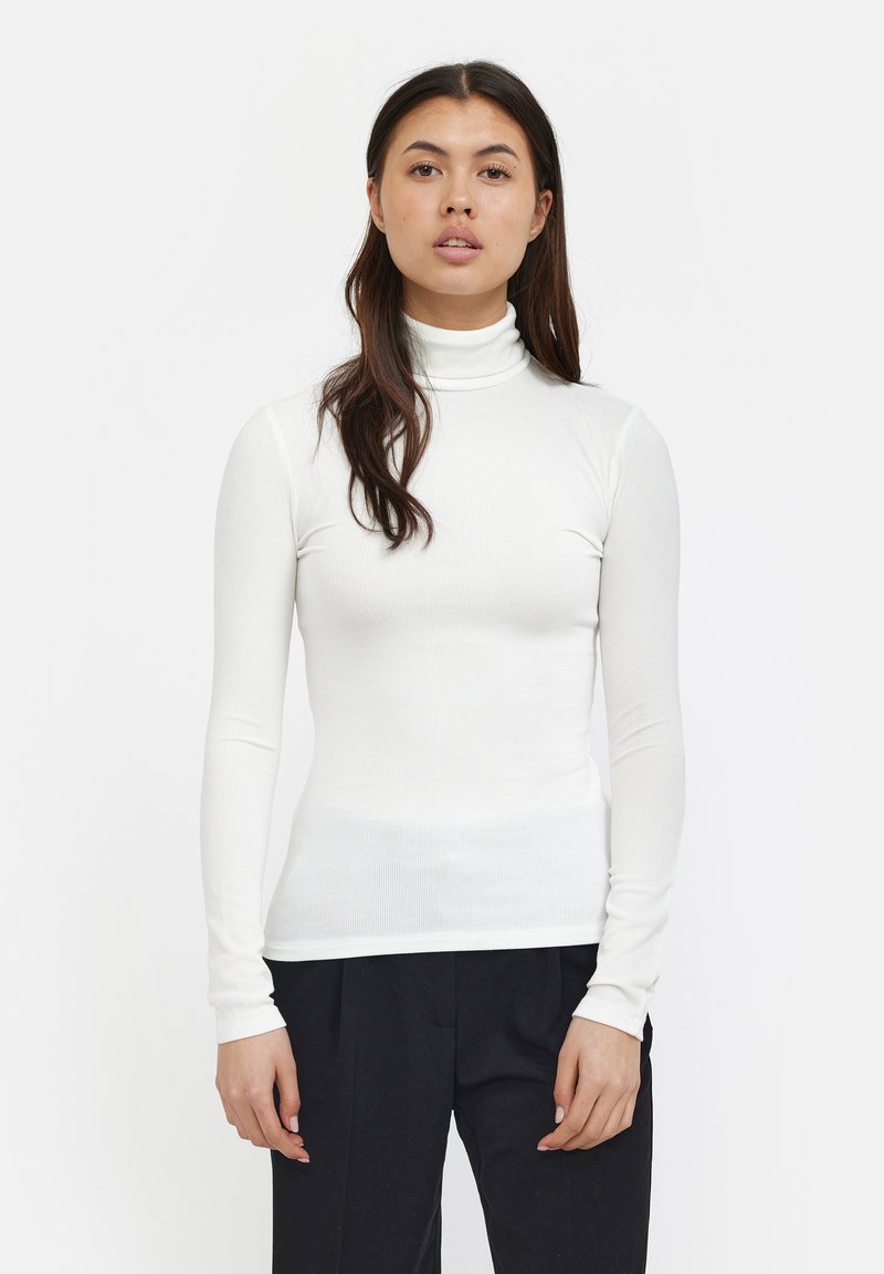 Hvid ribbet turtleneck top med lange ærmer, tætsiddende design og glat tekstur. Parret med sorte bukser, der fremhæver den stilrene stil.