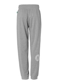 Grå sweatpants lavet af blødt stof, med sidelommer, en taljeelastik og et cirkulært logo på venstre ben.