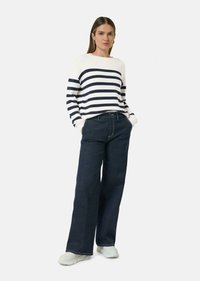Marineblauwe en witte gestreepte trui met een relaxte pasvorm, gecombineerd met donkere wide-leg jeans en witte sneakers. Zachte gebreide textuur en casual ontwerp.