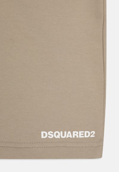 Tissu en coton beige avec une texture lisse, présentant le logo blanc "DSQUARED2" dans le coin inférieur droit.