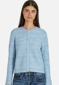 Cardigan azzurro chiaro realizzato in tessuto testurizzato, con scollatura rotonda, maniche lunghe, tasche frontali e dettagli decorativi con bottoni.