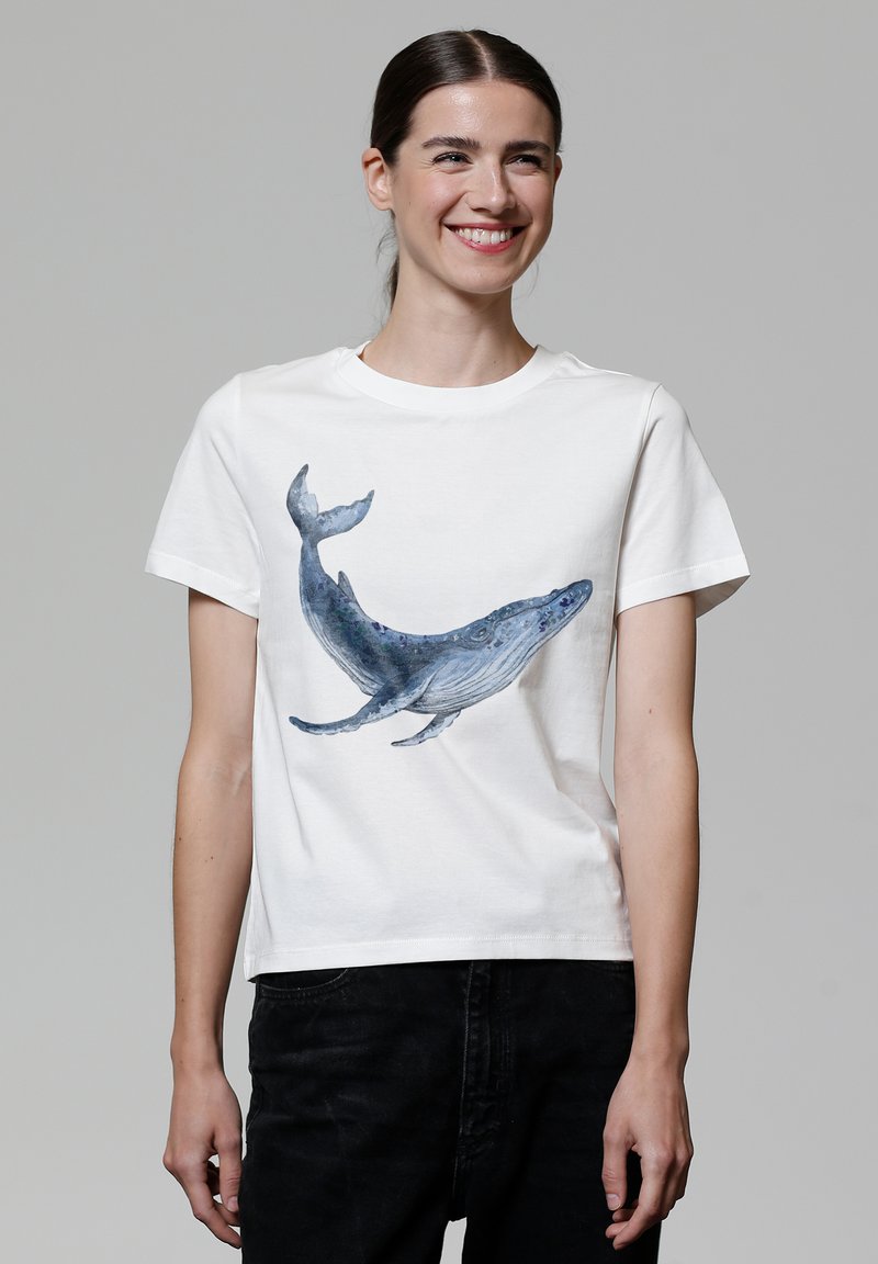 Weißes Baumwoll-T-Shirt mit einem blauen Wal-Design auf der Vorderseite. Das Shirt hat einen Rundhalsausschnitt und kurze Ärmel, mit einer lockeren Passform.