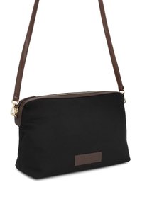 Μαύρη τσάντα χιαστί από καμβά με λείο καφέ δερμάτινο φερμουάρ και ρυθμιζόμενο ιμάντα. Διαθέτει απλό σχέδιο και δερμάτινη πινελιά.
