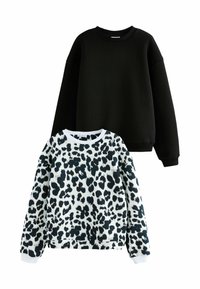 Due felpe esposte: una in nero uniforme, l'altra bianca con macchie leopardate nere. Entrambe hanno maniche lunghe e colli tondi.
