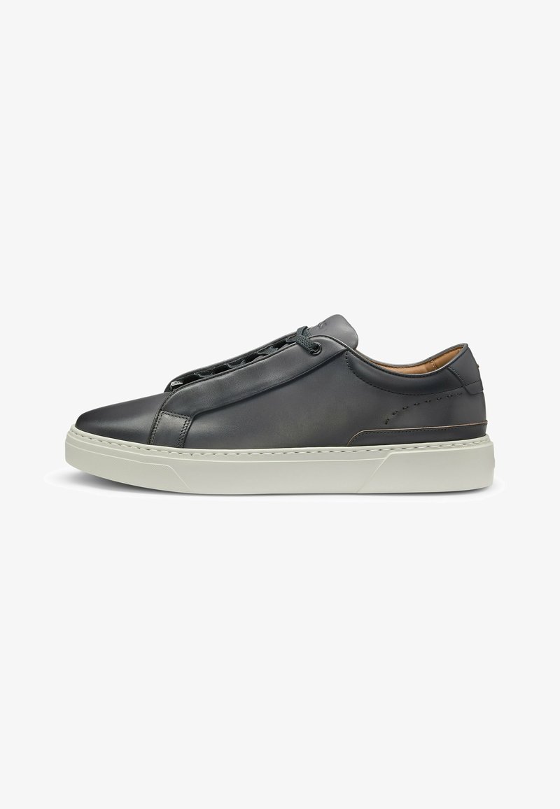 Black leather sneaker featuring a rounded toe, minimalistic design, and grey rubber sole. Includes lace closure and subtle stitching details.
