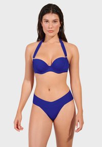 Modrý bikiny set pozostávajúci zo štruktúrovaného podprsenkového vrchu s kosticami a nastaviteľnými krčnými popruhmi, doplnený o vysoké nohavičky.