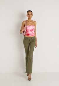 Ροζ φλοράλ τοπ χωρίς τιράντες, χακί φαρδιά παντελόνια και σανδάλια με τακούνι. Η τσάντα έχει παγιέτες. Τοποθετημένο σε απλό λευκό φόντο.