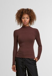 Braunes Langarmshirt mit hohem Kragen und schmaler Passform. Hergestellt aus einem glatten, dehnbaren Stoff, der ein einfaches Design ohne sichtbare Muster aufweist.