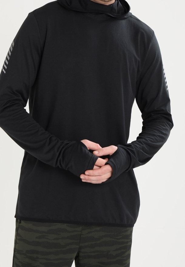 Musta pitkähihaisen hupparin, jossa on peukaloaukot; siinä on sileä pinta ja hillitty harmaa raidoitus hihoissa. Kuosiset vihreät housut.