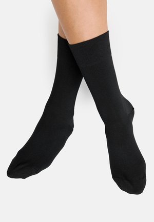 Schwarze Socken mit gerippten Bündchen, aus einem glatten Stoff gefertigt. Sie haben eine Standardlänge, die den Knöchel bedeckt, ohne sichtbare Muster oder Logos.