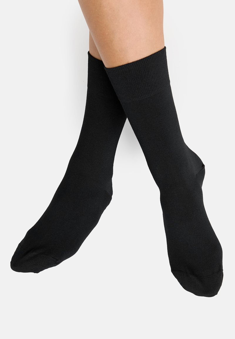 Calcetines negros con puños acanalados, hechos de una tela suave. Presentan una longitud estándar que cubre el tobillo, sin patrones ni logotipos visibles.
