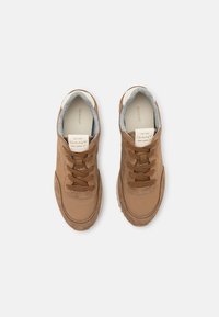 Brown athletic shoes featuring suede and textile materials, round toe, flat laces, gray inner lining, and textured rubber sole.