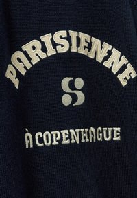 Tengerész színű pulóver anyag, krém színű hímzéssel. A szöveg ívben olvasható "PARISIENNE" felirattal, alatta "à COPENHAGUE", középen pedig egy grafika.