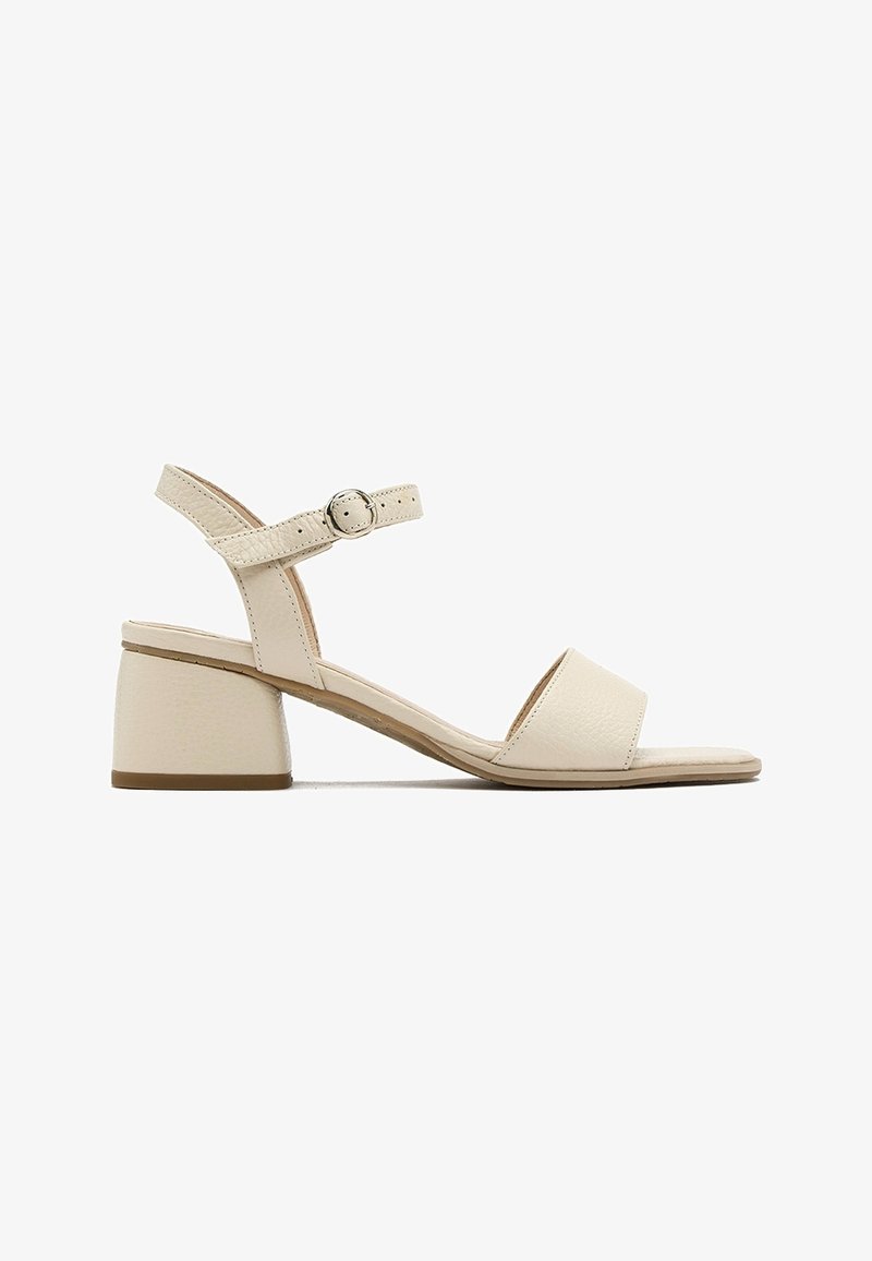 Sandale beige à bout ouvert avec un petit talon bloc et une bride de cheville fermée par une petite boucle ronde.