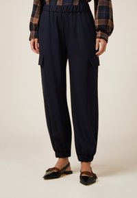 Pantalones cargo en color navy con una cintura elástica y puños, que cuentan con dos bolsillos laterales. Elaborados con una tela suave y ligera.