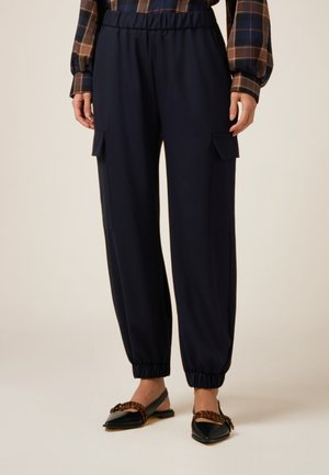 Pantalons cargo marine avec une taille élastique et des poignets, dotés de deux poches latérales. Fabriqués à partir d'un tissu lisse et léger.