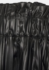 Saia pregueada preta feita de couro sintético texturizado, com um cós elástico e um brilho suave ao longo do tecido franzido.