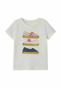 Hvid t-shirt med illustrerede sko: lyserød stribet slippers, hvid slippers med hjerter og blå slippers med striber. Blødt bomuldsstof.