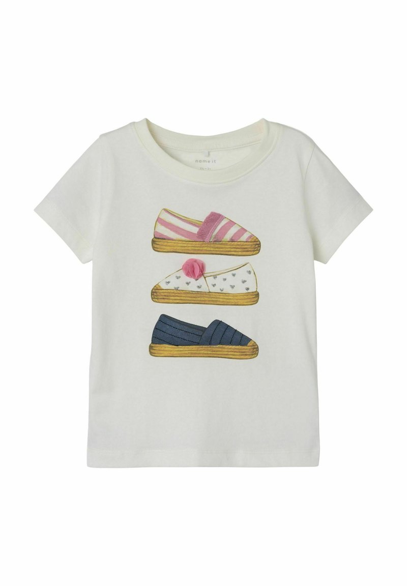 Hvid t-shirt med illustrerede sko: lyserød stribet slippers, hvid slippers med hjerter og blå slippers med striber. Blødt bomuldsstof.