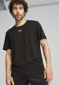 Camiseta negra de manga corta hecha de un tejido suave, con un logo blanco de Puma en el pecho y un diseño de corte relajado.