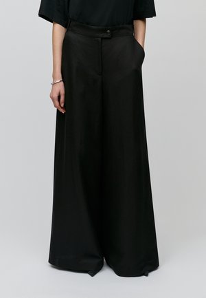 Pantalones negros de pierna ancha hechos de una tela suave, con cierre de botón y bolsillos laterales, con un diseño limpio y minimalista.