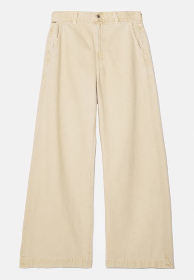 Beige széles lábú nadrág, pamutból készült. Gombos és cipzáras záródással, két oldalsó zsebből és steppelt szegélyből áll. Sima felület.