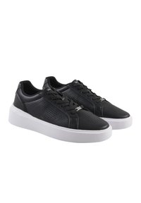 Zapatillas de cuero negro con diseño perforado, suela plana de goma blanca, cordones en la parte delantera y acentos de hardware plateado.