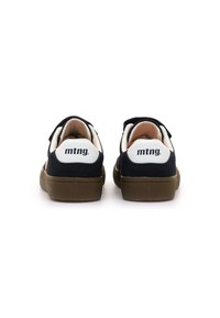 Zapatillas de ante azul marino con un refuerzo blanco en el talón, con correas de velcro y una suela de goma marrón. Logo de texto "mtng." en la parte trasera.