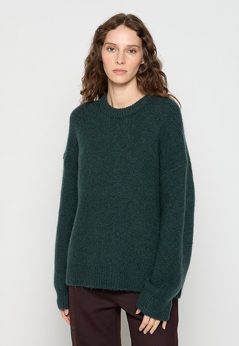 Dunkelgrüner, übergroßer Strickpullover mit rundem Ausschnitt, langen Ärmeln und weicher Textur. Verfügt über einen gerippten Saum und Rippbündchen.