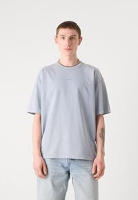 Lyseblå bomulds t-shirt med afslappet pasform, korte ærmer og rund halsudskæring. Har et lille broderet logo på brystet.
