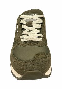 Oliemilgroene sneaker met een gestructureerde bovenkant, platte witte veters, gevoerde kraag en contrasterende witte rubberen zool. Met logo aan de zijkant.