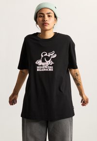 Schwarzes, übergroßes T-Shirt aus Baumwolle, mit einer pinken Grafik eines Hasen und Text. Das Shirt hat kurze Ärmel und einen runden Halsausschnitt.