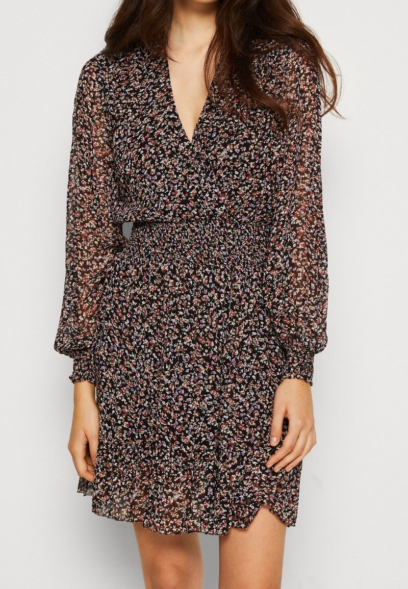 Schwarzes Blumen Kleid mit langen transparenten Ärmeln, taillierter Taille und rüschensaum. Mit V-Ausschnitt und zartem, mehrfarbigem Blumenmuster.