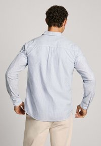 Camisa de rayas de manga larga en azul claro y blanco, con un cuello clásico, puños abotonados y un dobladillo curvado con un yugo en la parte posterior.
