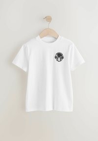 T-shirt bianco a maniche corte in cotone, con una grafica nera di una scimmia che indossa cuffie sulla parte sinistra del petto.