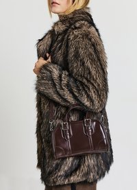 Manteau en fausse fourrure avec des rayures brunes et noires, associé à un petit sac à main en cuir synthétique marron foncé, avec des éléments en métal argenté et une bandoulière amovible.