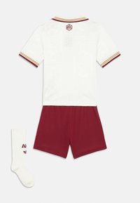 Vitt tröja med geometriskt mönster, randig mörkröd och gul krage, matchande mörkröda shorts och vita strumpor med mörkröd branding.