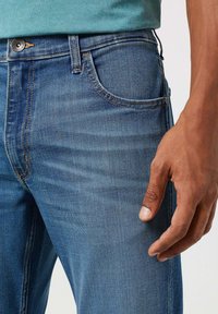 Jeans in denim di un lavaggio azzurro chiaro, con un classico design a cinque tasche, dettagli di cucitura a vista e una vestibilità regolare.