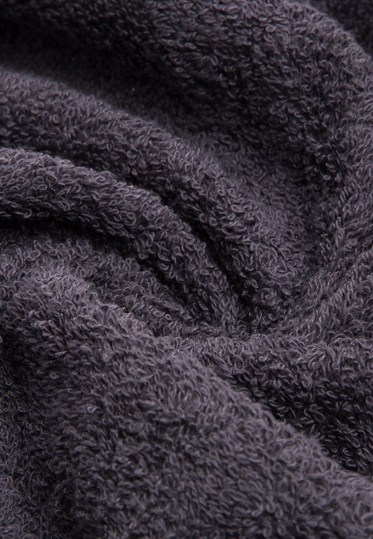 Dunkelgraues Baumwollhandtuch mit einer weichen, strukturierten Oberfläche, das ein plüschiges, geschlungenes Design aufweist. Der Stoff wirkt zerknittert und gefaltet.
