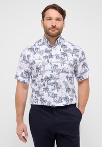 Korte mouwen shirt van witte stof, met een blauw tropisch patroon van palmbomen en landschapen; klassieke kraag en een ontspannen pasvorm.