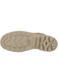 Semelle de botte en caoutchouc beige avec un motif texturé comprenant des profondes rainures et des accents en relief pour une meilleure traction. Nom de la marque emboutie sur la semelle.