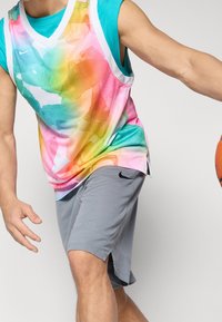 Jersey de baloncesto de Nike con un diseño abstracto colorido en rosa, azul y amarillo. Combinado con pantalones cortos grises que presentan un acento de logo.