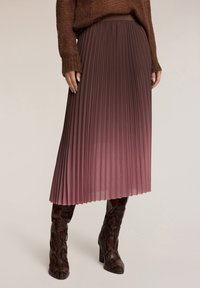 Fållad midikjol i gradient mauve tyg med en mjuk textur. Kombinerad med bruna, snakmönstrade högklackade stövlar.