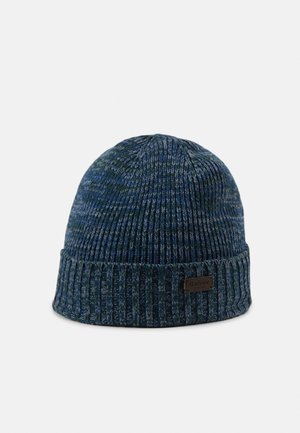 Bonnet en tricot côtelé bleu et gris avec revers plié et petite étiquette brune « Barbour » sur le revers, posé sur un fond uni.