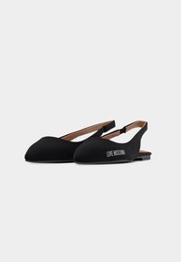 Μαύρα μπαλαρίνες slingback με μυτερά δάχτυλα και την επιγραφή "LOVE MOSCHINO" στο πλάι, με χαμηλό τακούνι και ελαστικούς ιμάντες.