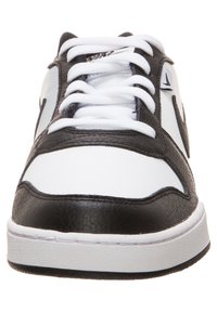 Czarno-białe trampki z gładką skórzaną cholewką, białymi sznurowadłami, płaską gumową podeszwą i subtelnymi akcentami logo po bokach.