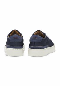 Navy blue slip-on shoes featuring a textured upper, smooth accents, and a white rubber sole. Simple design with subtle branding on the heel.