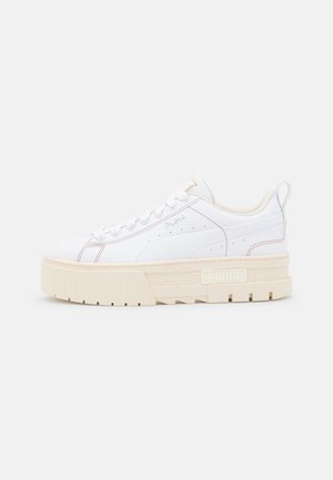 Baskets blanches basses Puma avec semelle épaisse beige texturée, fermeture à lacets sur le devant et détails de couture subtils sur un fond uni.