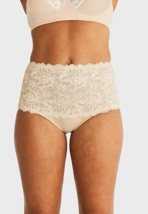 Vrouw draagt beige kanten ondergoed met hoge taille en bijpassende beha, zichtbaar van middenrif tot middenbovenbeen tegen een witte achtergrond.